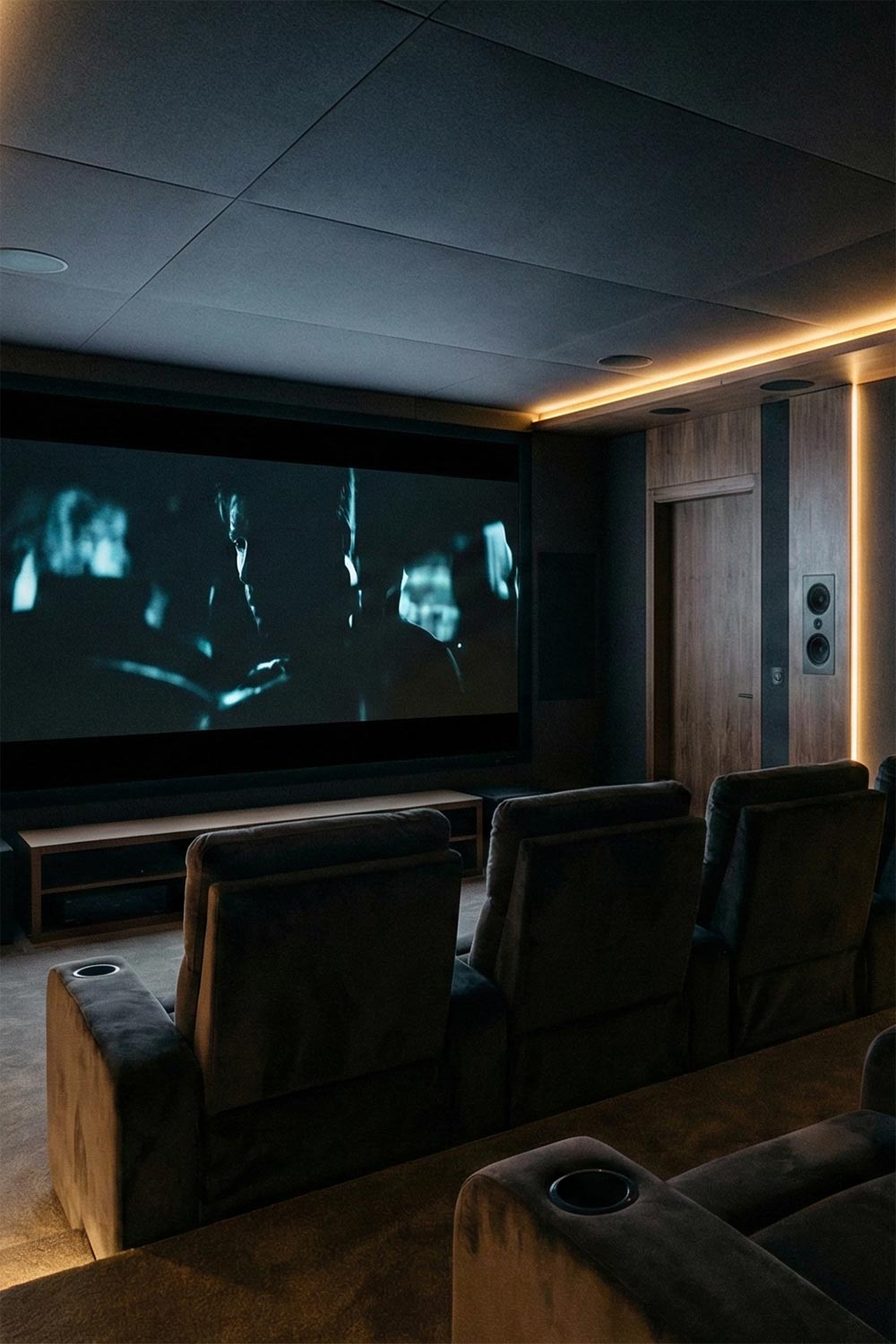 Sleek home theater featuring wood paneling, tiered velvet seating, and ambient cove lighting