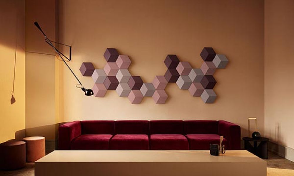 Stylish living room with geometric wall panels and a deep red velvet sofa under warm lighting