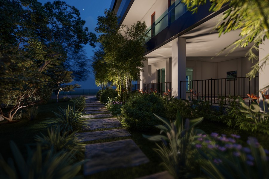 Modern home exterior illuminated by strategic outdoor lighting along a stone pathway surrounded by lush greenery and flowering plants at dusk.