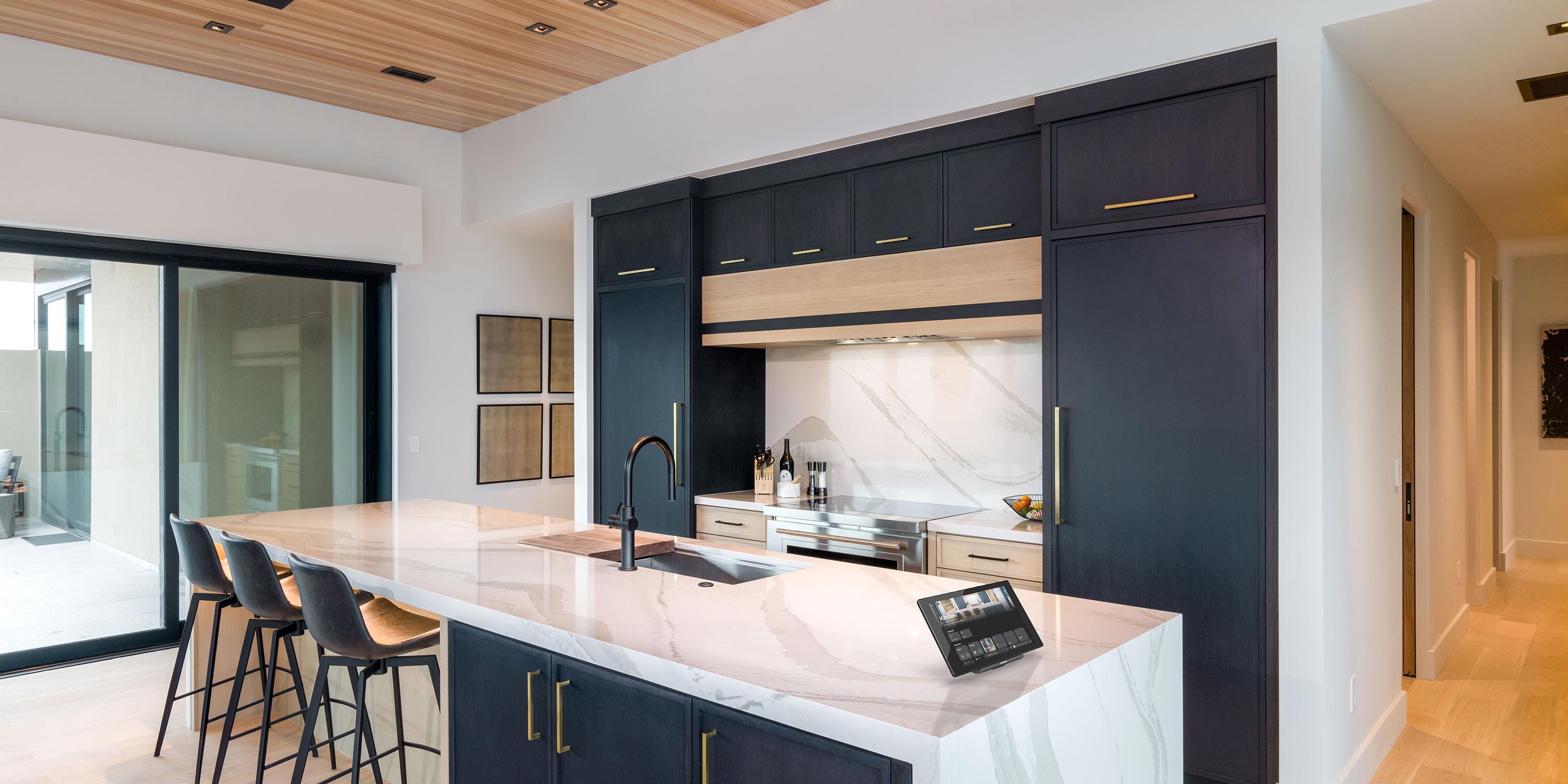 Contemporary kitchen featuring a marble countertop island, sleek cabinetry, and bar stools, with a large sliding door to the patio.