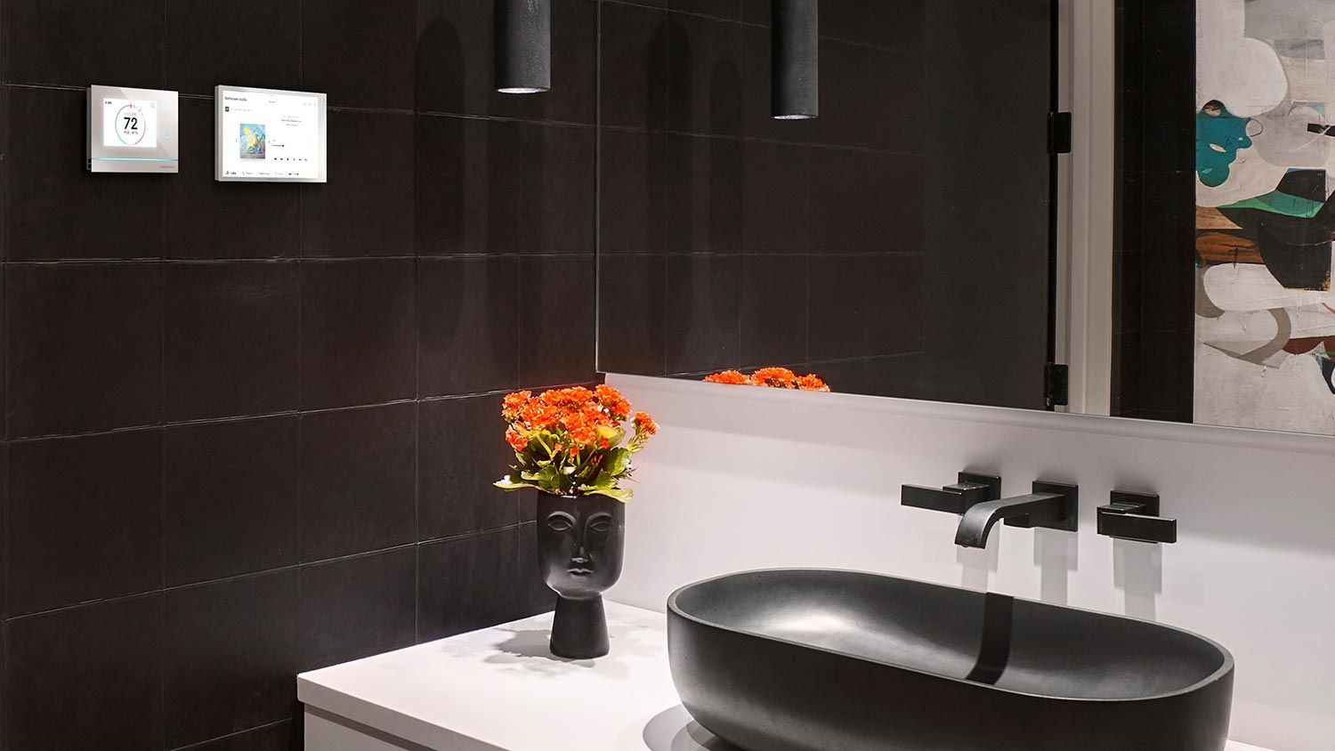 A modern bathroom with a black stone sink and a minimalistic vase holding flowers, featuring wall-mounted smart control panels.